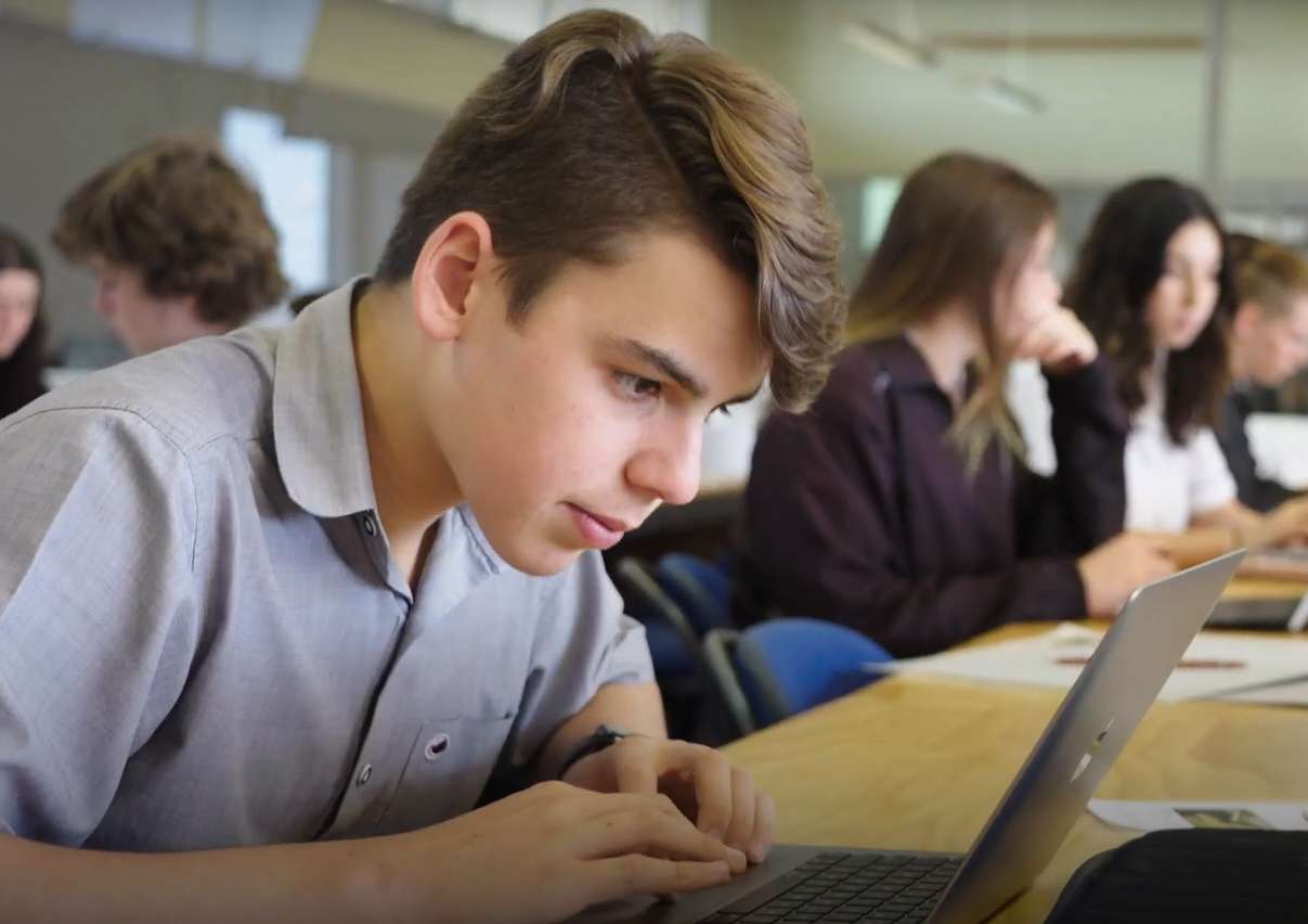 A male student using a laptop in a classroom