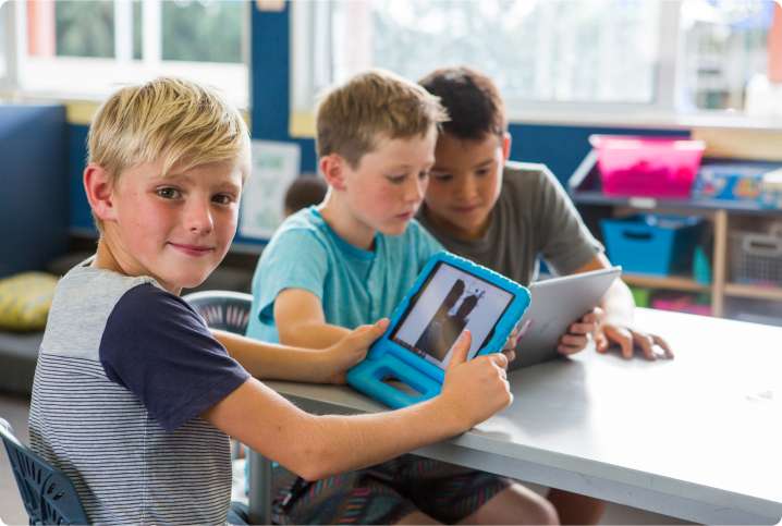 A group of students sitting at a table looking at a tablet