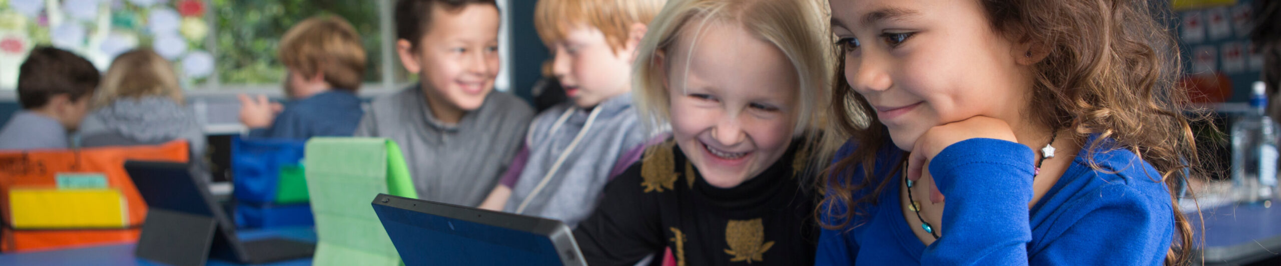 Two girls looking at a tablet in a classroom