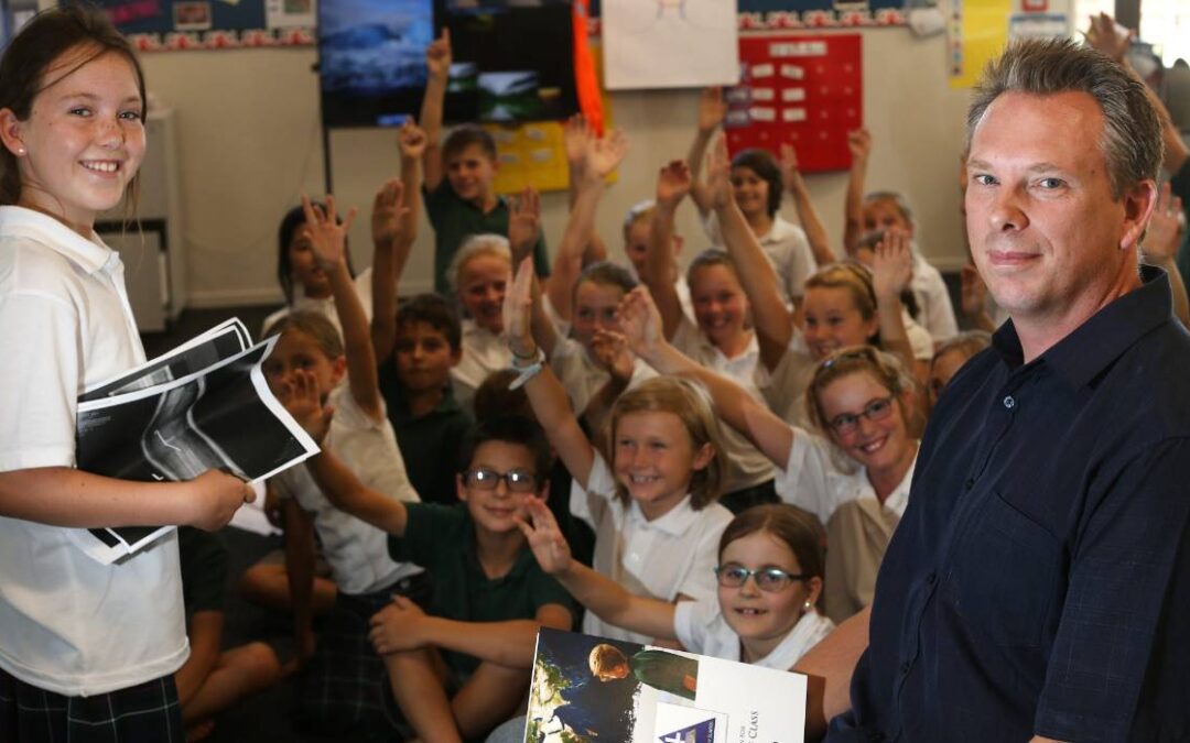 A school principle standing in front of a classroom full of children