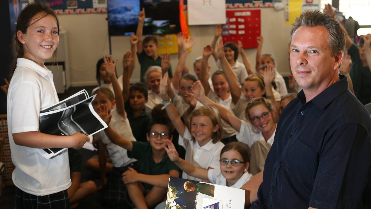 A school principle standing in front of a classroom full of children