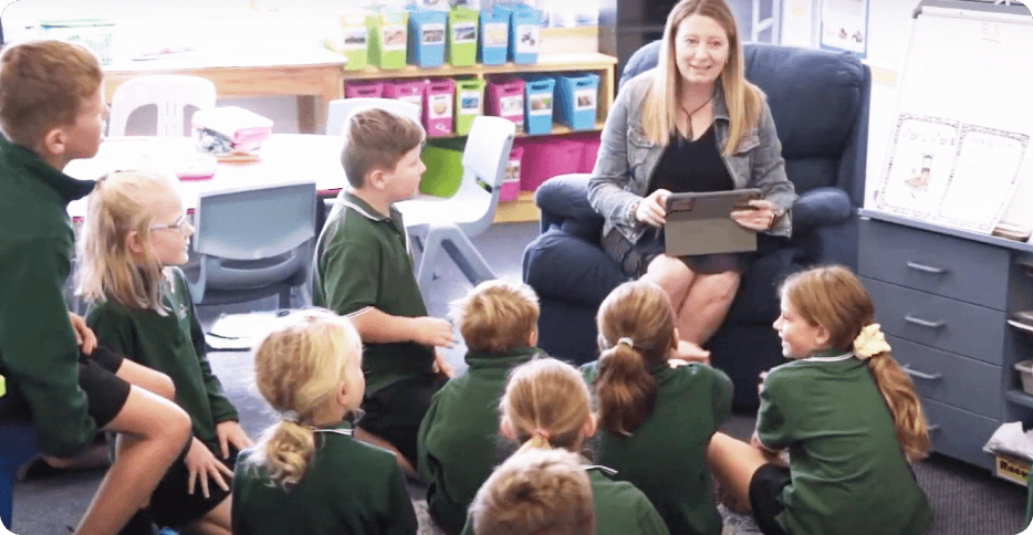 A woman teacher is sitting in front of a group of children