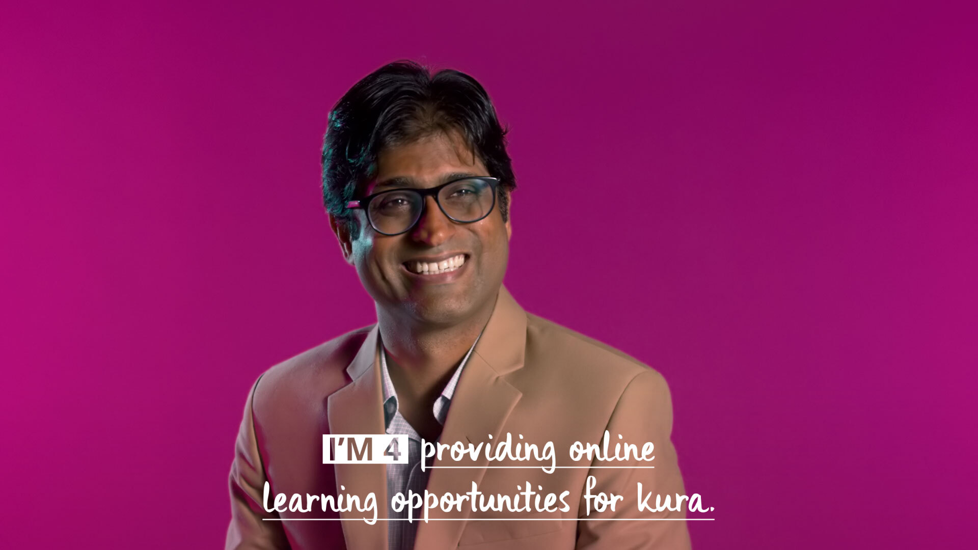 Man smiling sitting in front of a plum coloured background with caption: I'm for providing online learning opportunities for kura