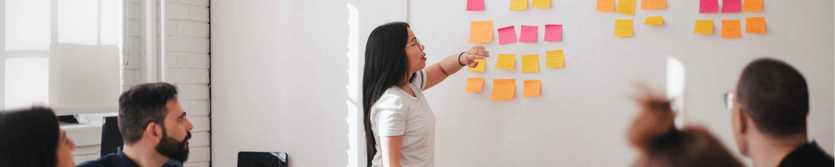 Woman placing sticky notes on a whiteboard