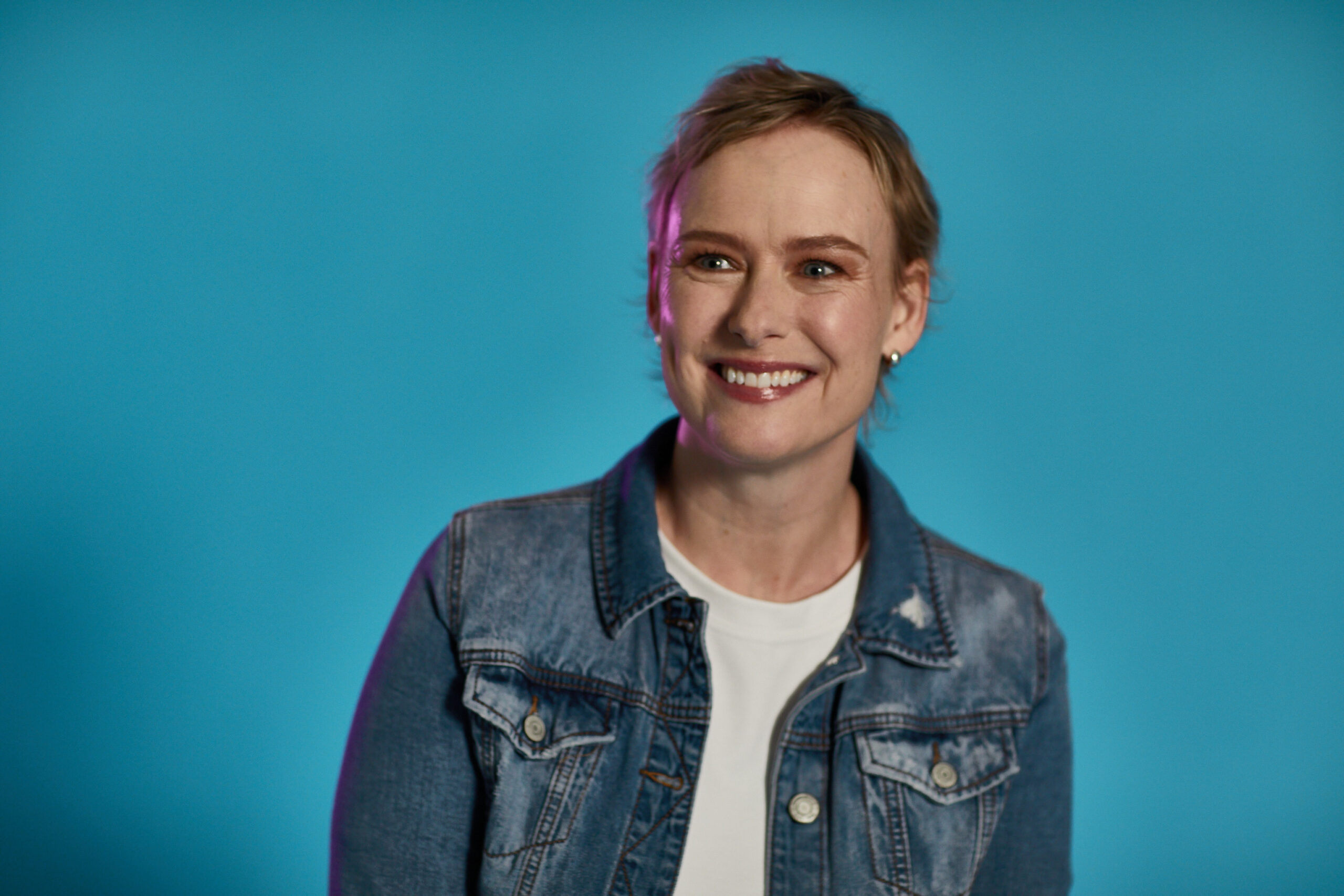 Woman smiling sitting in front of a blue background