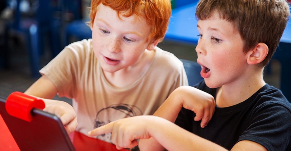 Two young boys using a tablet in a classroom