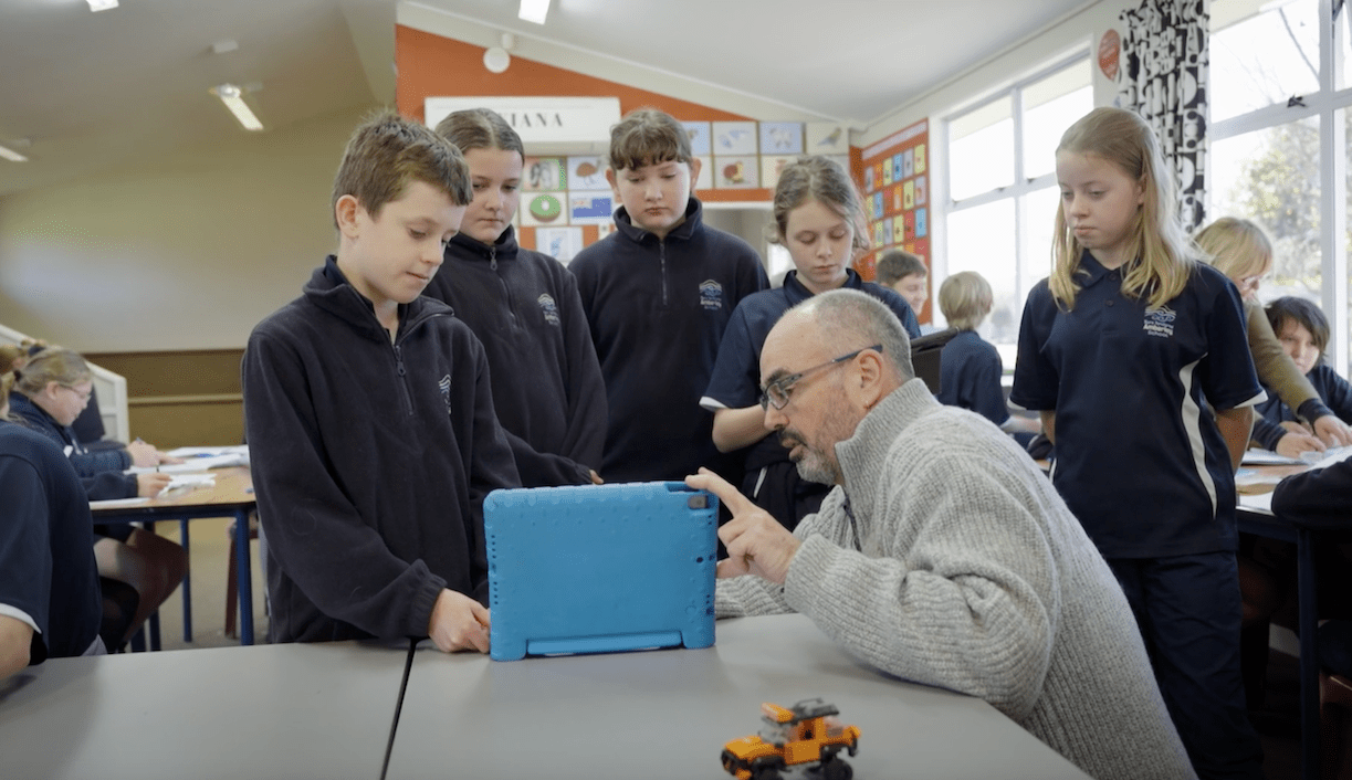 Teacher and students gathered around device in classroom