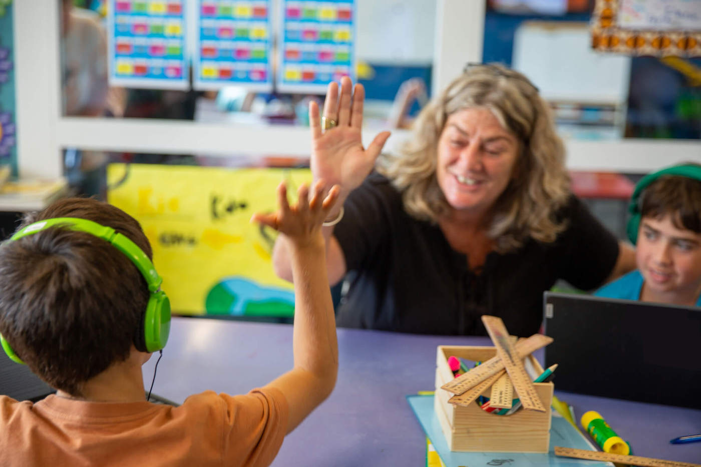 A teacher is giving a high five to a child in a classroom
