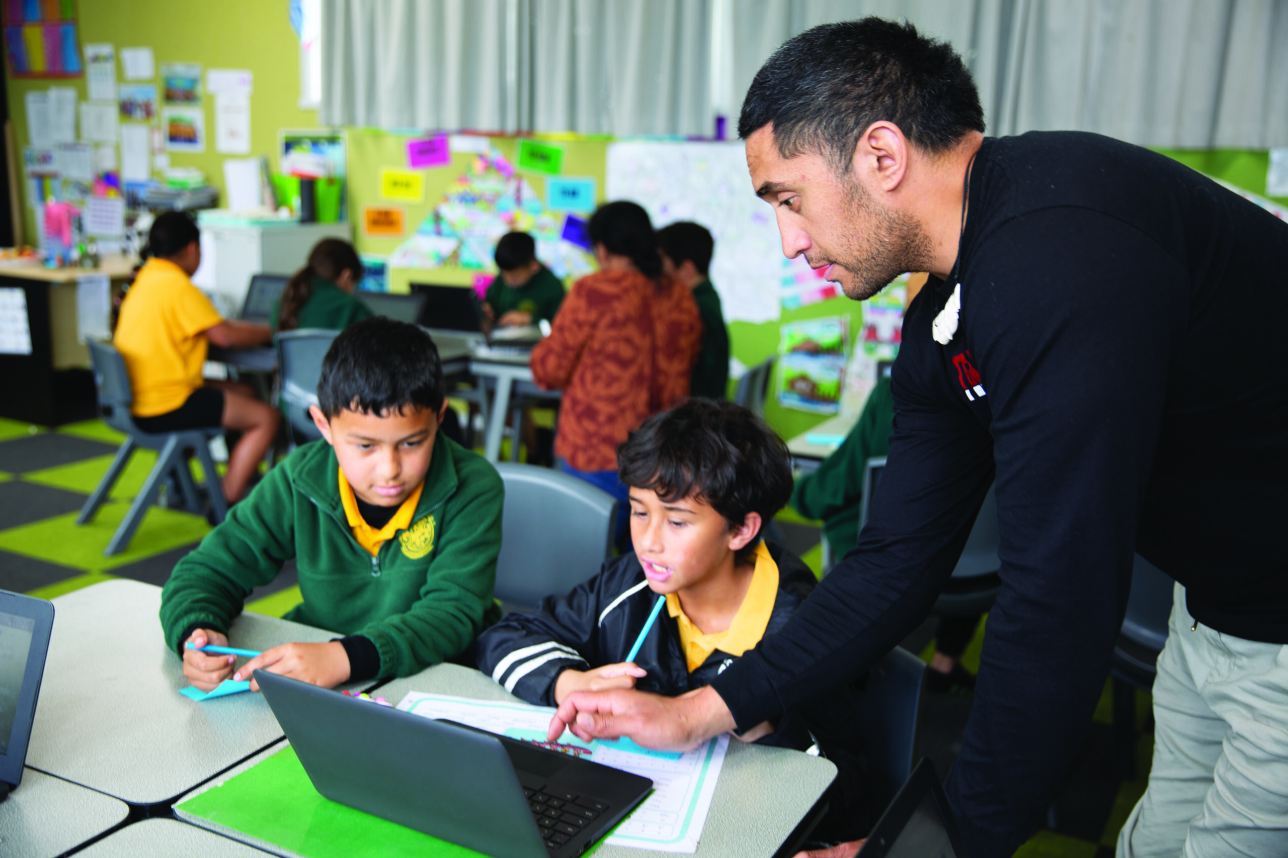 Teacher with two students using a laptop in class